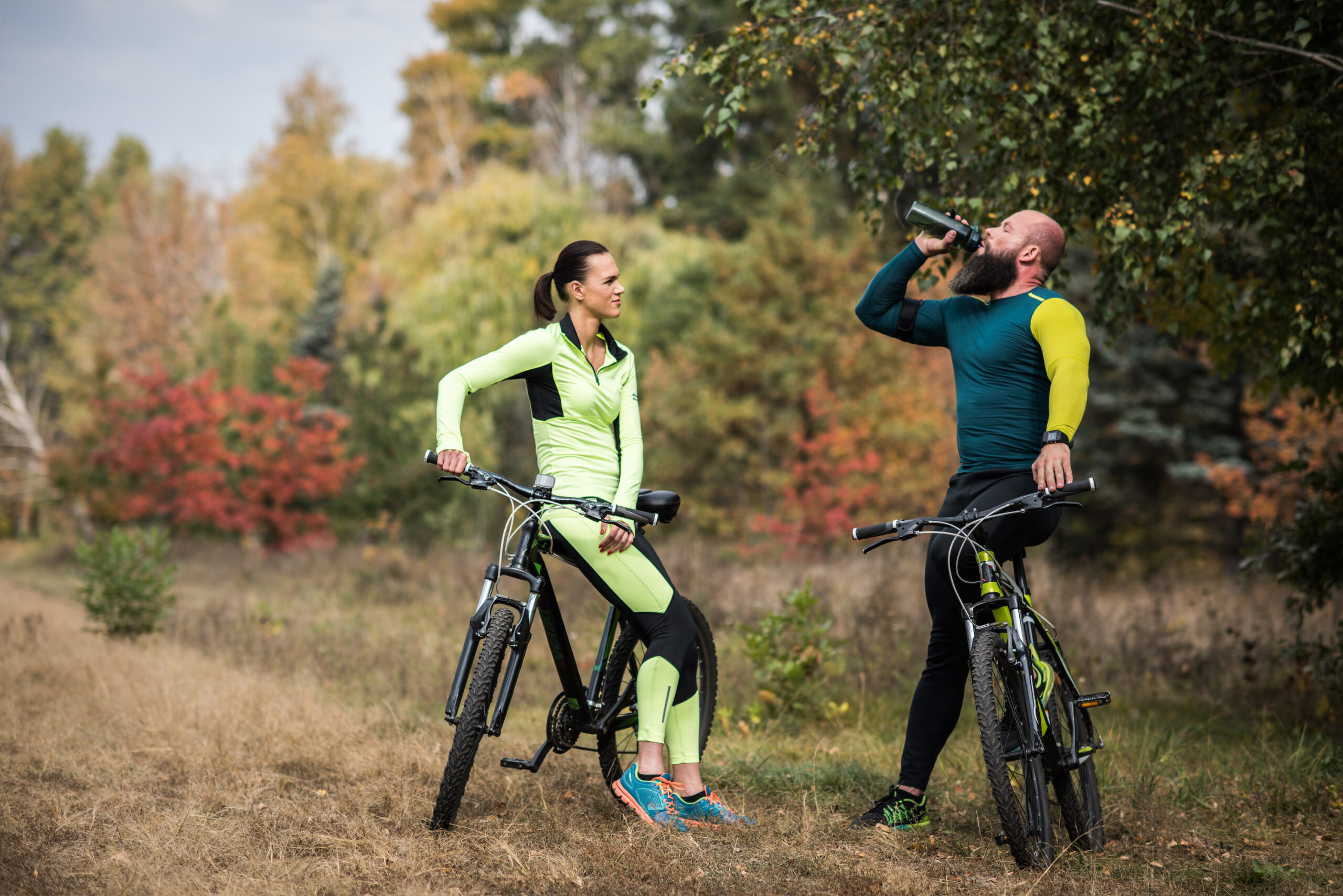 Two people taking a water break while riding their bicycles