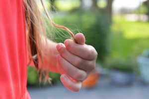 Person holding a strand of their hair