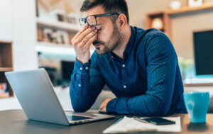 Person feeling tired and fatigued while working on a laptop
